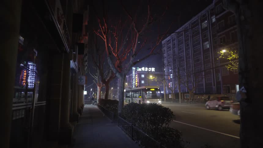 Buses and cars driving down a city street at night
