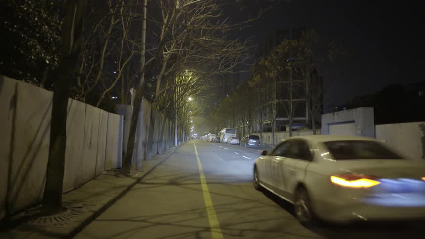 A white car driving down the road with its headlights on
