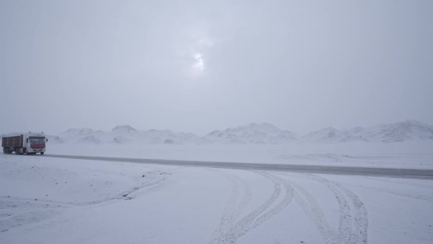 A truck drives through a snow-covered mountain area