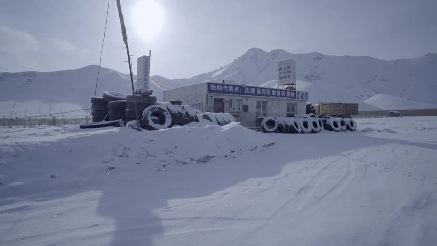 Tires surround a small building on a snowy day