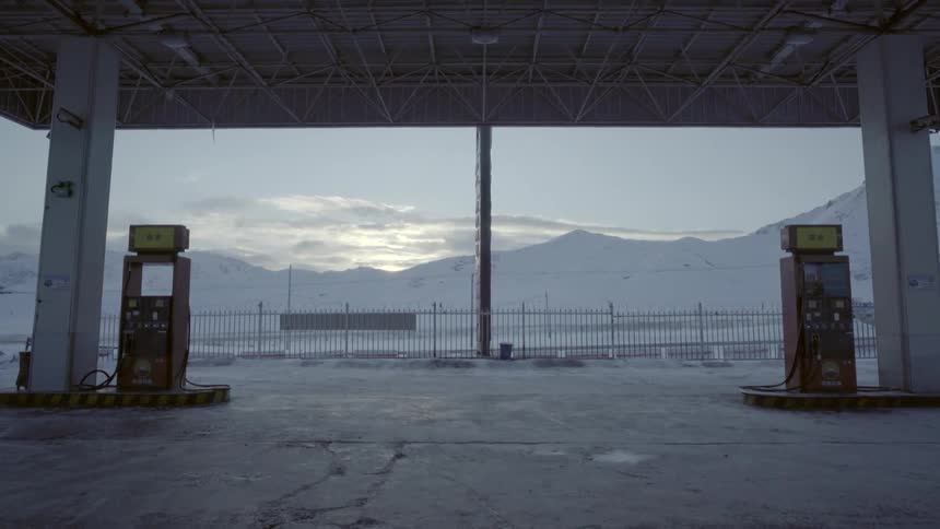 Clouds over snow covered mountains behind gas pumps