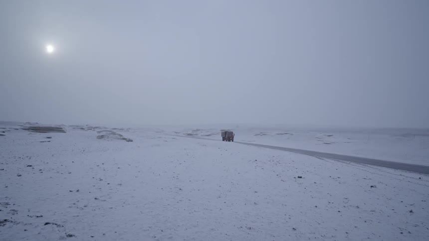 Truck driving down road in snowy landscape