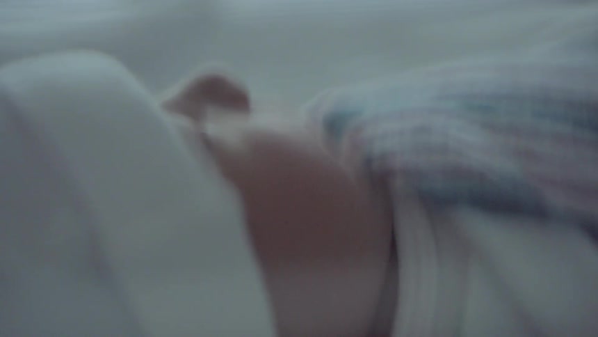 A baby sleeping under a small blanket