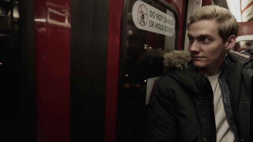 A young man stands on a train