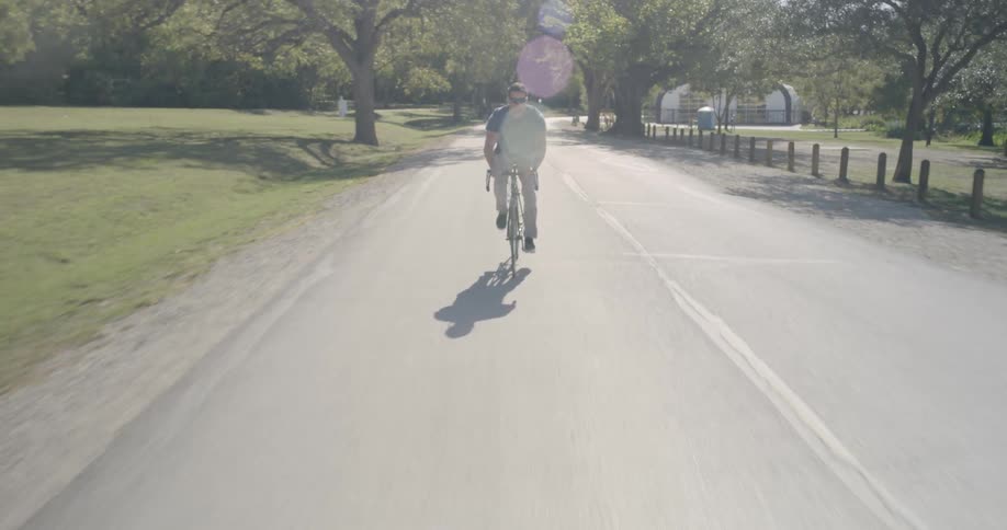 A man rides a bike on a rural road on a sunny day