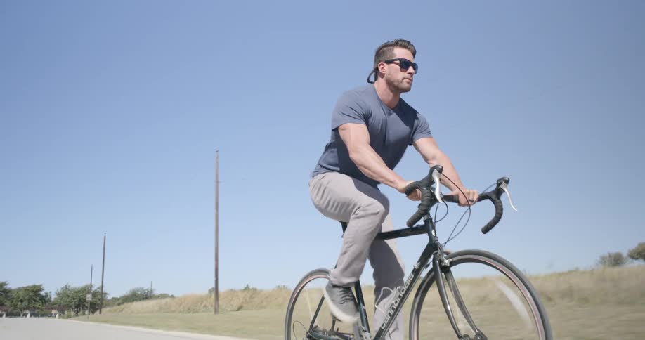 A man rides a bicycle outside on a sunny day