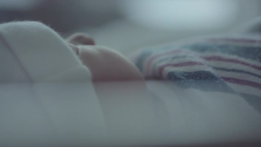 A newborn baby sleeps while wrapped up in a blanket