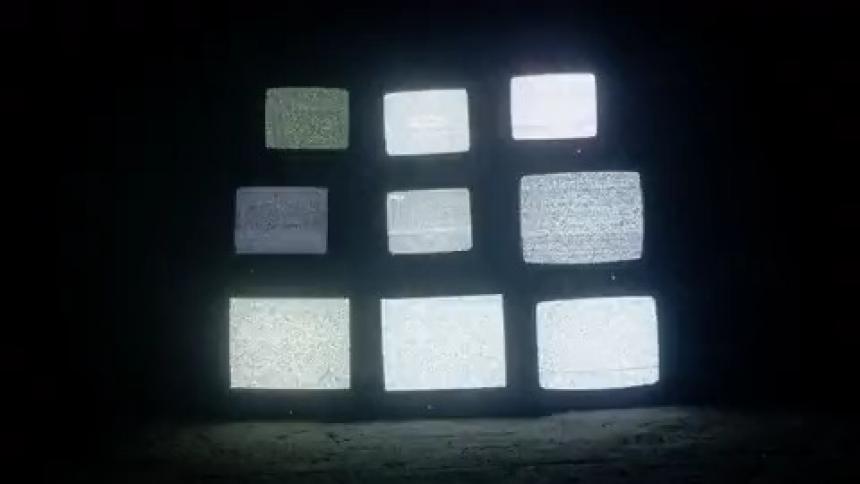 Tv screens stacked upon each other in a dark room