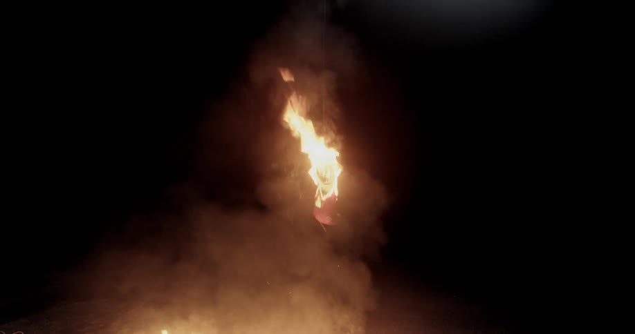 A piece of fabric that is hanging from a tree and is on fire