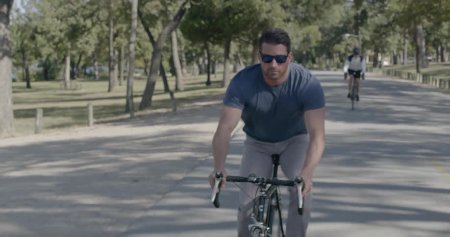 A man with shades riding a sports bike in a park
