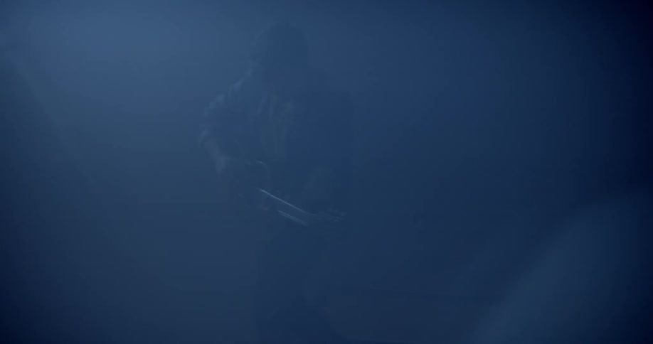 A musician plays a guitar on a dark stage
