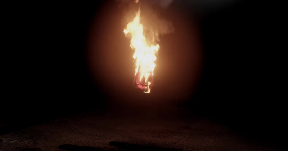 An object that is dangling in the middle of a darkened room burns brightly with a vigorous fire