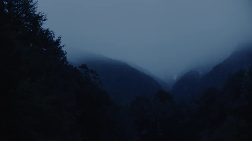 A canyon between mountains at night in the fog