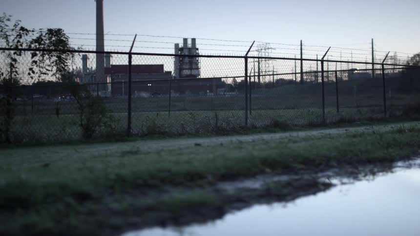 Industrial buildings sit behind a barbed wire fence