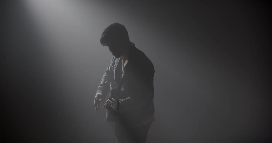Man plays guitar in a room filled with fog