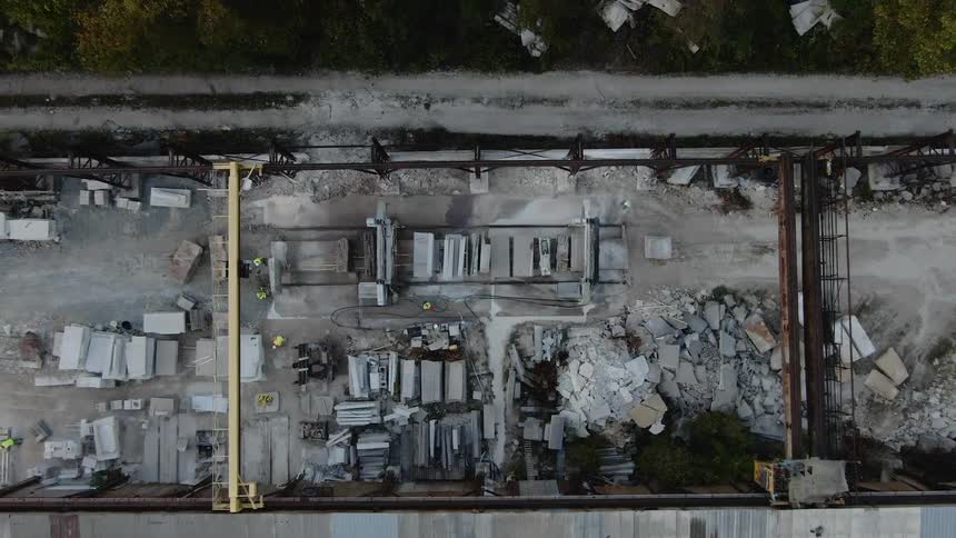 Construction workers walk around a site with broken rock and stone