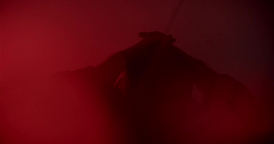 A person stands in a dark smokey room