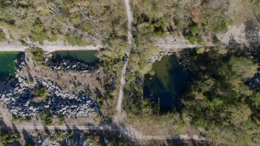 A vehicle drives down a dirt road and over a body of water