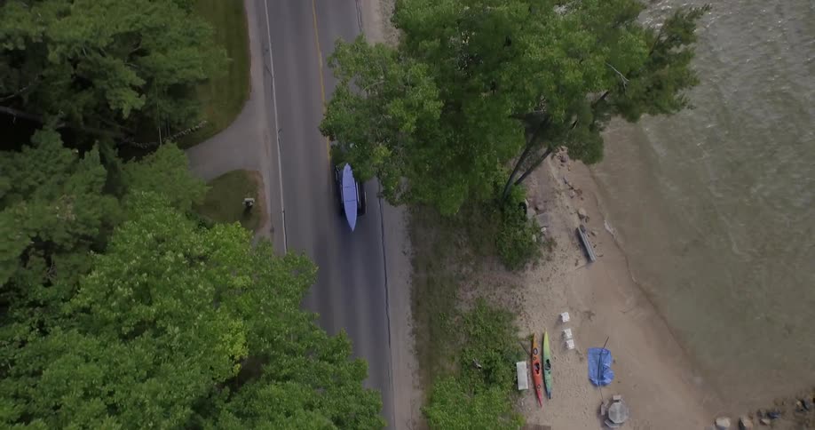 An aerial view of a truck is driving along a beach