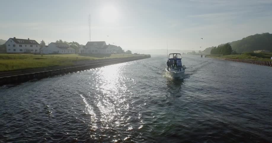The boat travels down the river as birds fly by