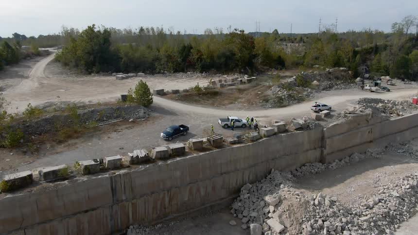 The trucks are parked along the broken wall of a work site