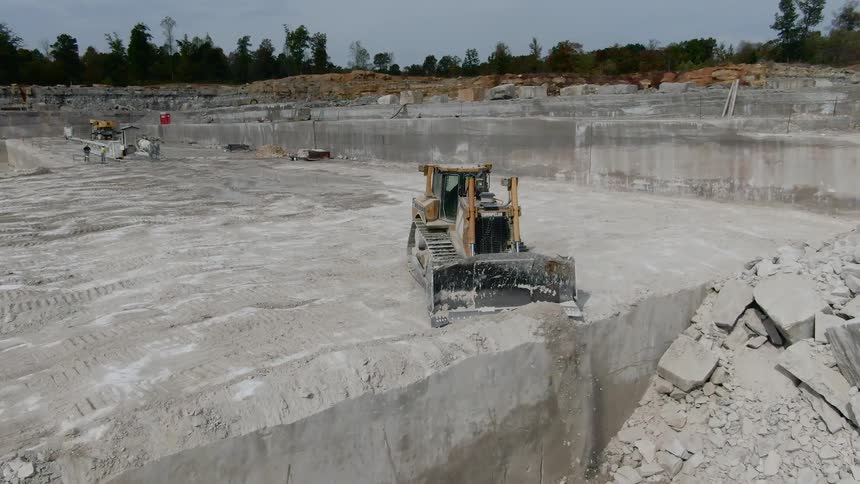 A bulldozer pushes cement over a edge at a construction site