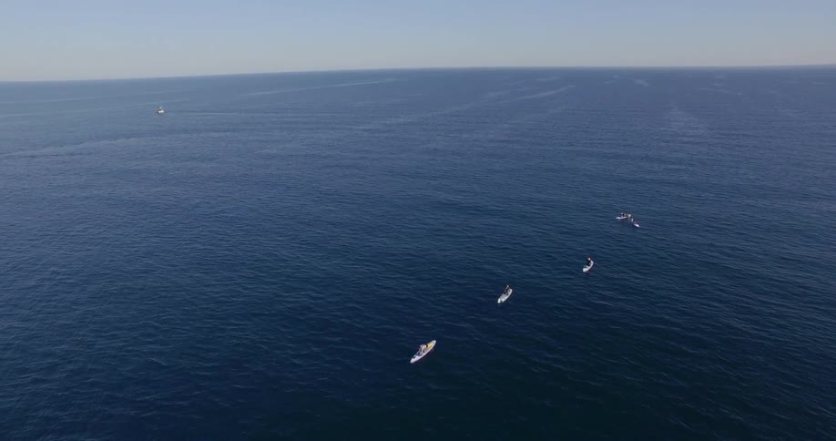 A line of boats follow each other in the ocean