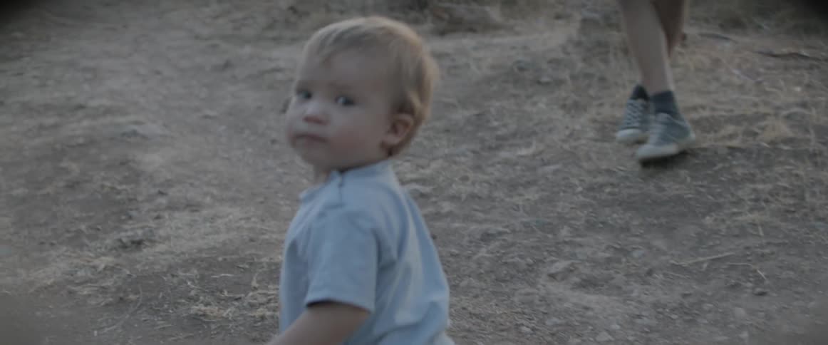 Toddler boy walks on the dirt road at dusk