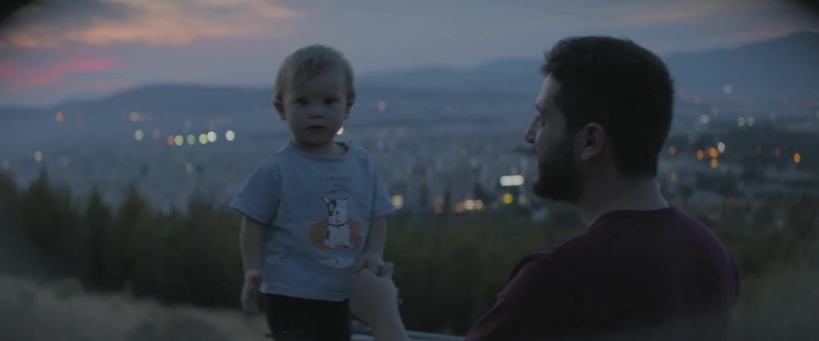 Toddler waves as his father holds his hand and smiles