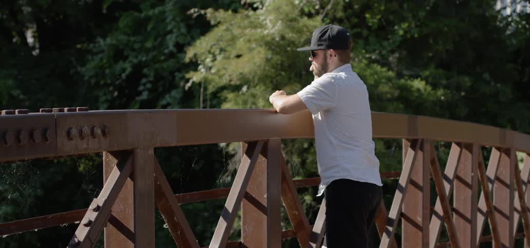 A man stands on a bridge and looks in to the distance