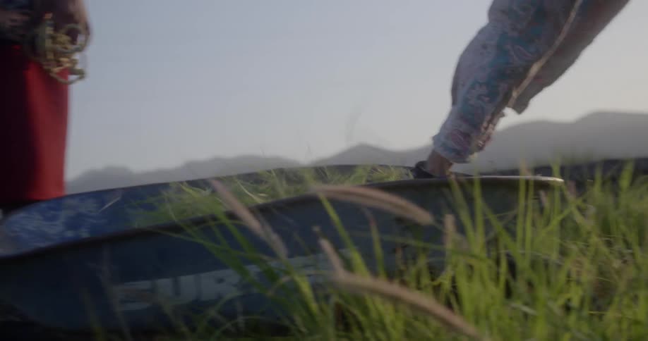 A man picks up clumps of grass and puts it in a wheelbarrow