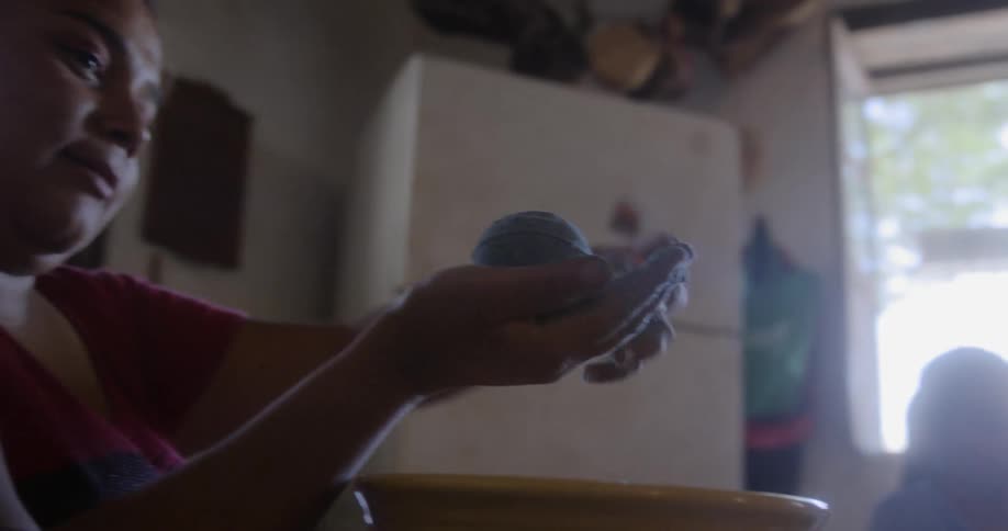 A child plays with sand in a bowl