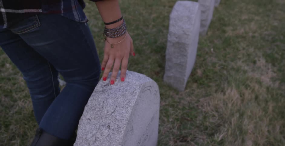A woman touches a headstone