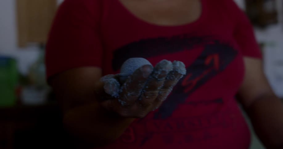 A woman making a blue powder ball with blue powder on her hands