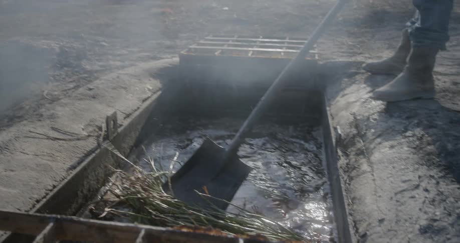 A man uses a shovel to remove vegetation from a well