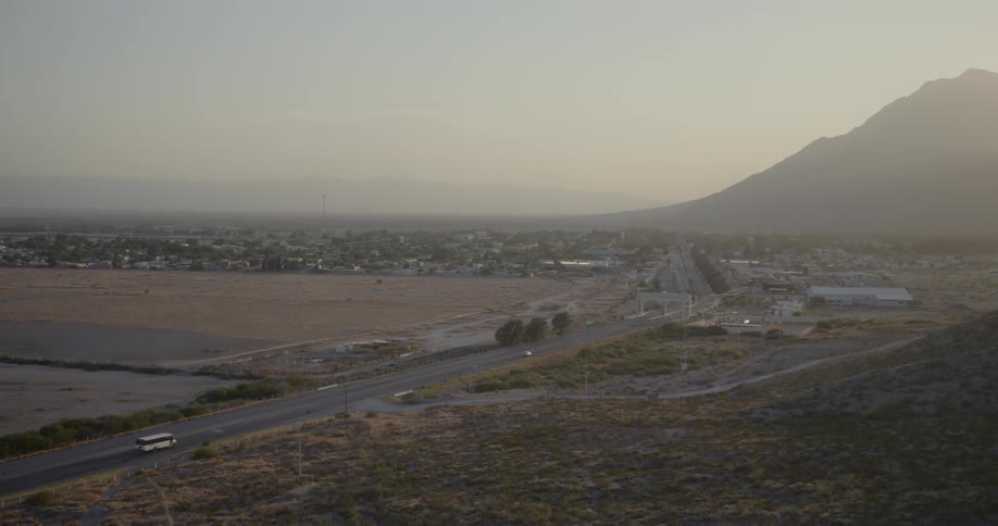 Highway passing through small town near mountain at sunset