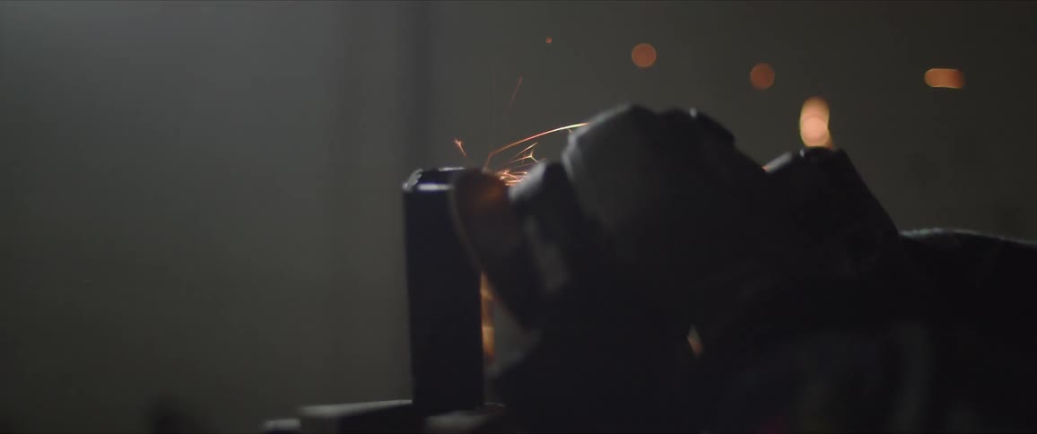 Worker using electric grinder circular saw to file a piece of metal