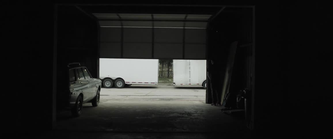 A garage door opens and a large trailer sits outside
