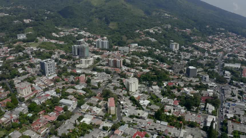 An aerial view of a sprawling city on a green mountain side