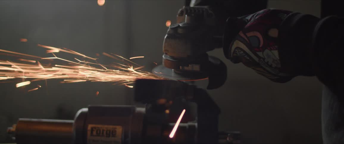 A man uses a grinding wheel on metal in a work shop