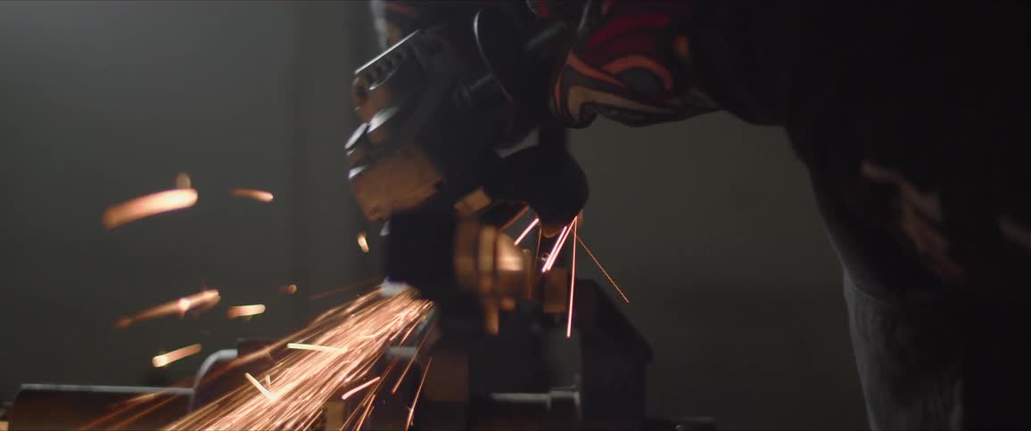 A person is grinding metal in a shop producing sparks