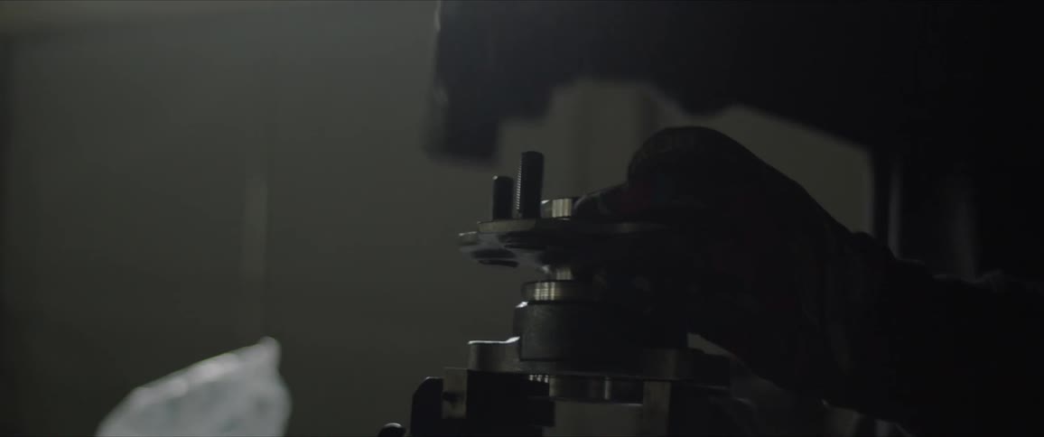 A person wearing gloves unpacks equipment and taps out long bolts using a hammer