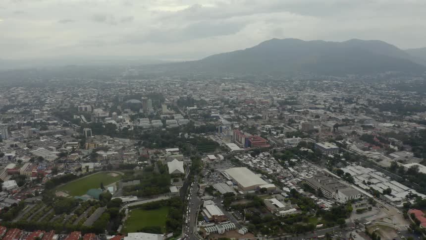 Rooftops and roads of a city at the base of a mountain on a cloudy day