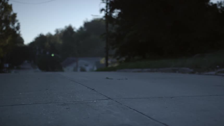 Traveling down an empty road with houses on each side at sunset