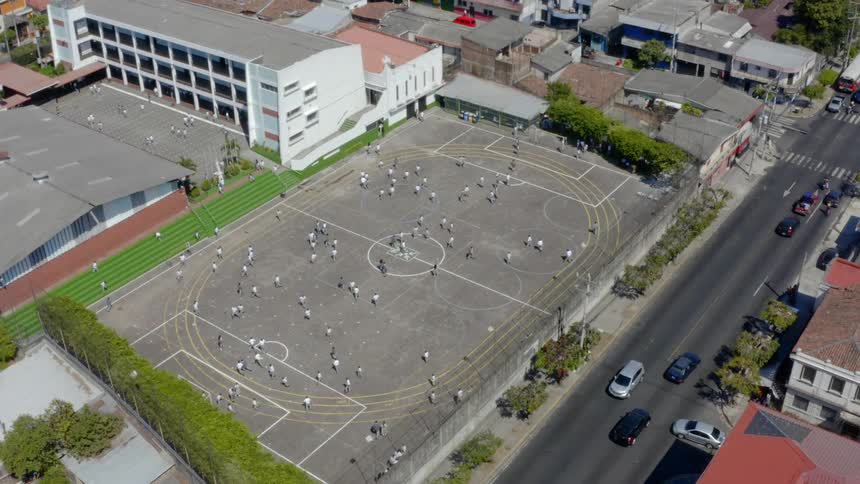 Teams playing soccer match on school soccer field near street