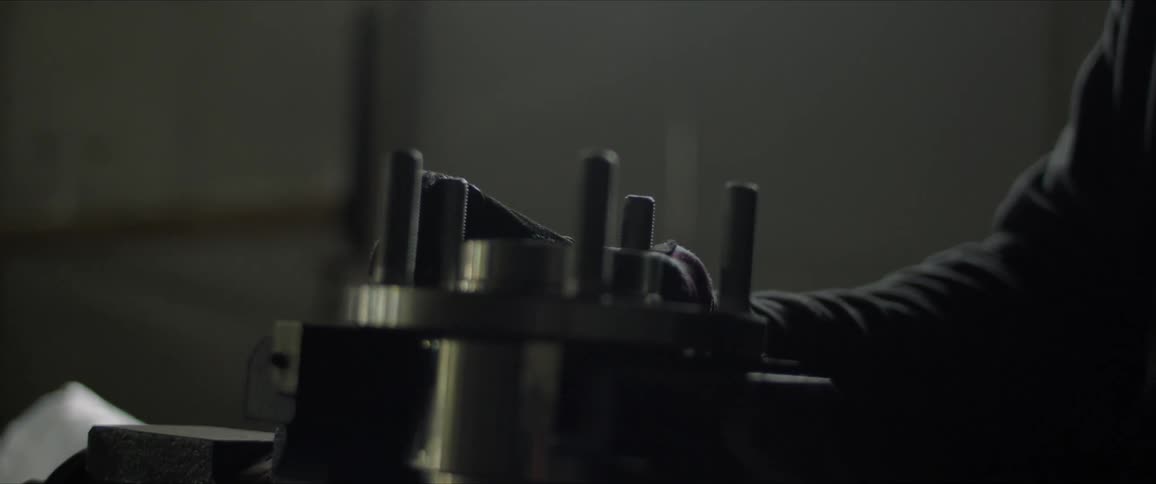 A man puts a metal object in a vice and hits it with a hammer