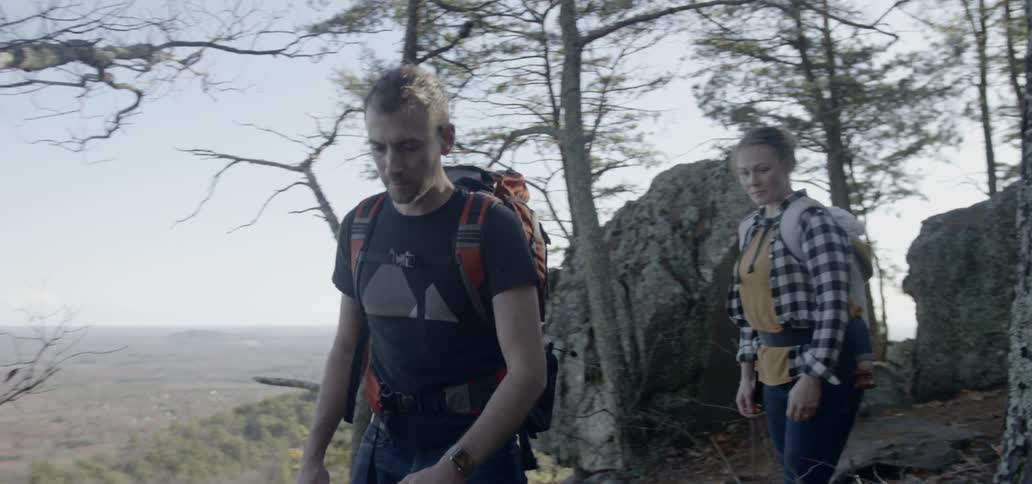 A family of three hike on the side of a mountain in the day time