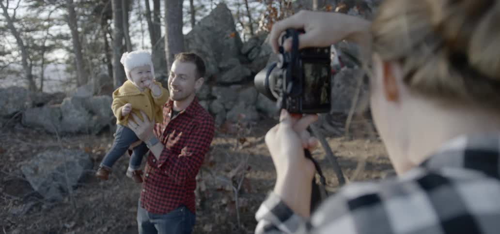 A woman takes a picture of a man and a baby
