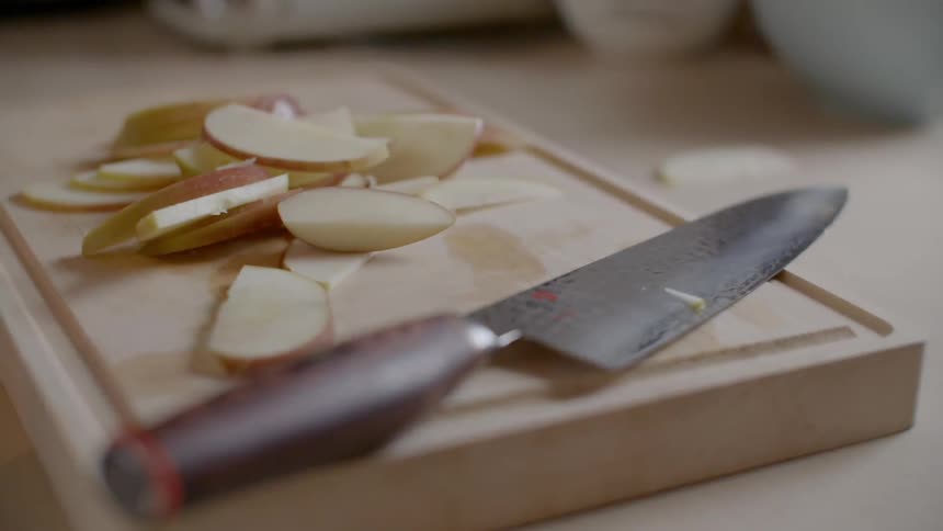 A knife is sitting next to a cut up apple