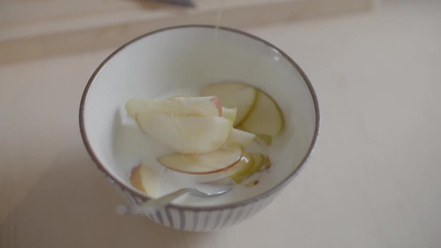 Honey is being poured on some fruit and yogurt